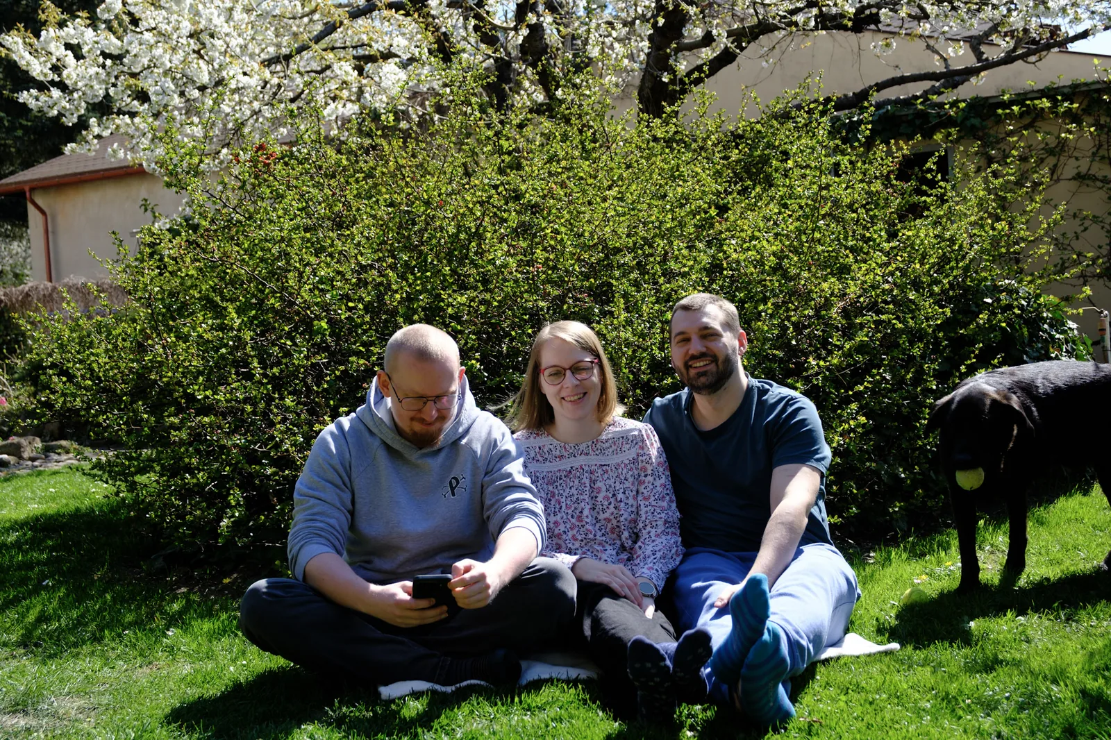 Piotr, Natalia and Tomasz sitting on the grass in their garden in Łódź, with their dog